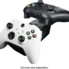 07e2f3fc-db52-4f60-8b43-6bb78da0a172 Two Xbox-style wireless controllers (white and black) resting on a charging dock, with the note 'Devices sold separately' shown below.