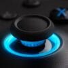 Version 1.0.0 Close-up of a textured black thumbstick with a blue LED ring on a game controller surface behind it, highlighting the illuminated ring area.