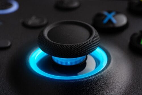 Version 1.0.0 Close-up of a textured black thumbstick with a blue LED ring on a game controller surface behind it, highlighting the illuminated ring area.