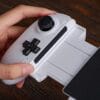 Version 1.0.0 Close-up of a white handheld game controller attachment held in a left hand, showing a black joystick and D-pad.