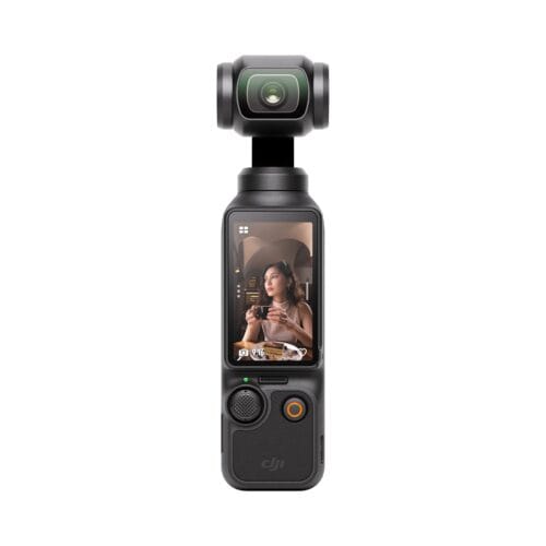 Close-up of a handheld camera gimbal with a lens on top; the gimbal's screen shows a woman sipping coffee indoors.