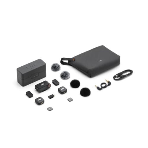 DJI camera accessories scattered on a white background: carrying case, charger, wireless transmitter, mics with windshields, cables and small accessories.