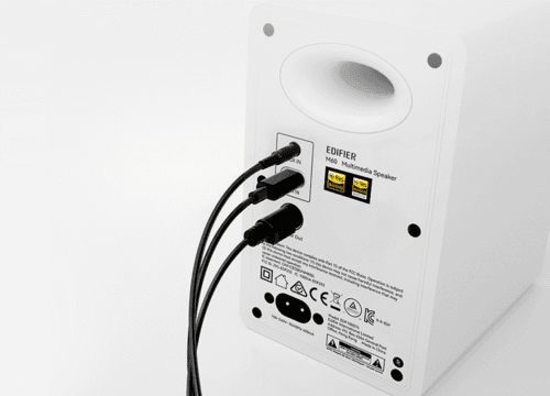 Rear view of a white Edifier M60 multimedia speaker with two black cables plugged into the input/output ports on the back panel