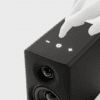 Hand tapping the touch controls (−, power, +) on a small black speaker.